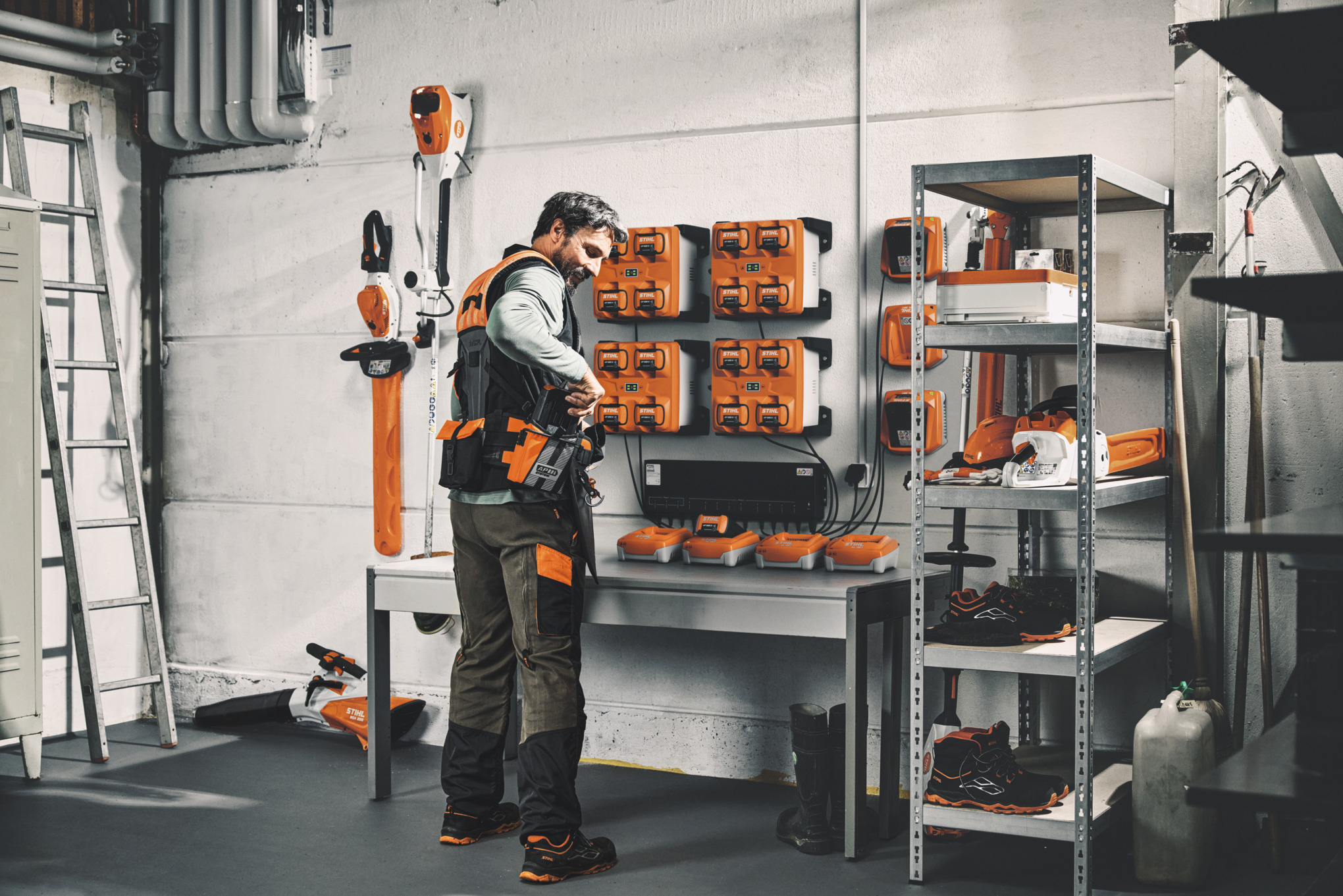 Mężczyzna w magazynie z narzędziami i akumulatorami STIHL nosi modułowy system uprzęży STIHL ADVANCE X-Flex 